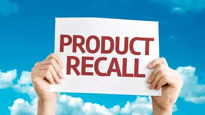 a person holding a sign that says "product recall"