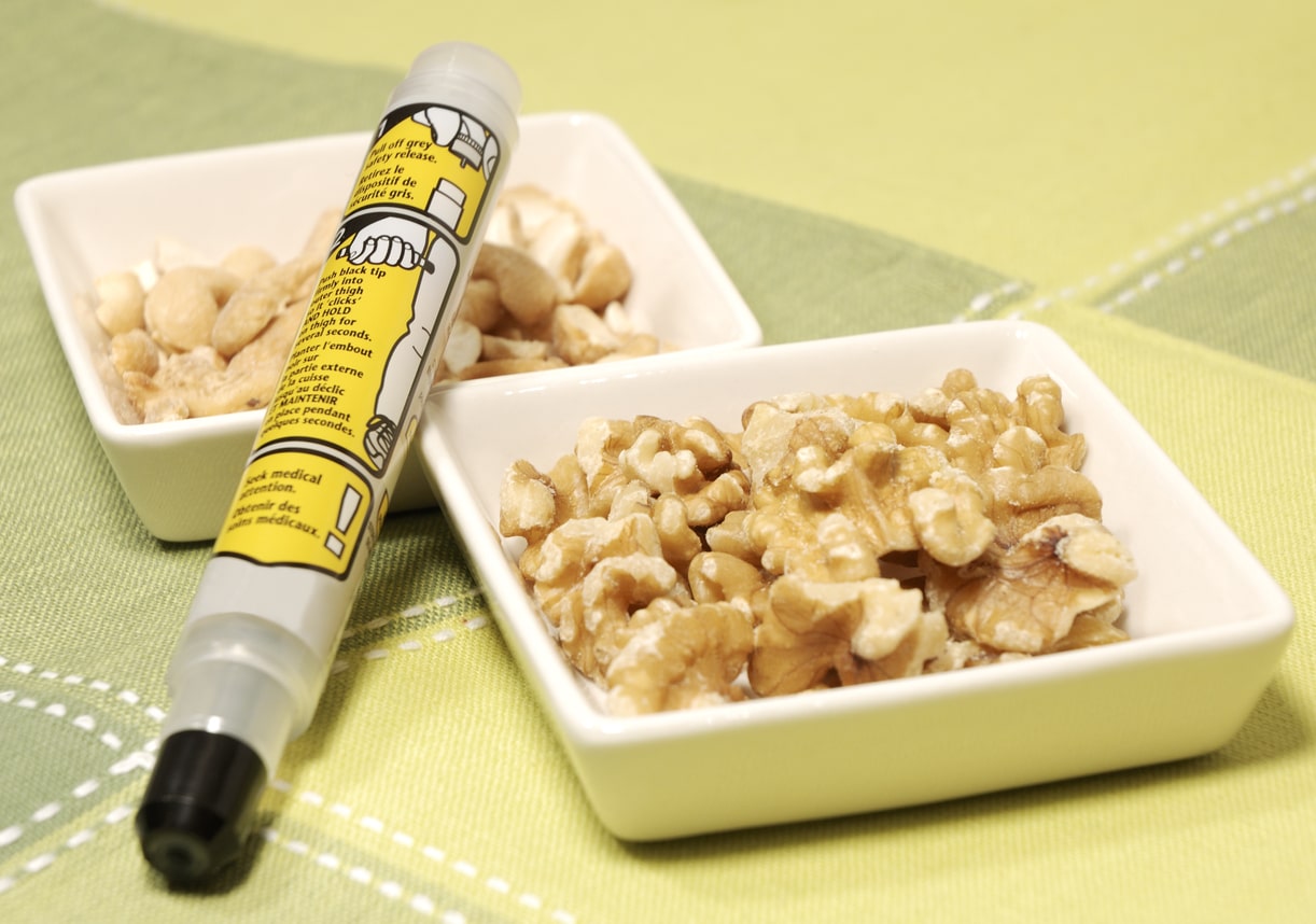 epipen laying on top of two cups of nuts