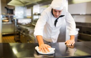 A chef wiping the counter top in the kitchen