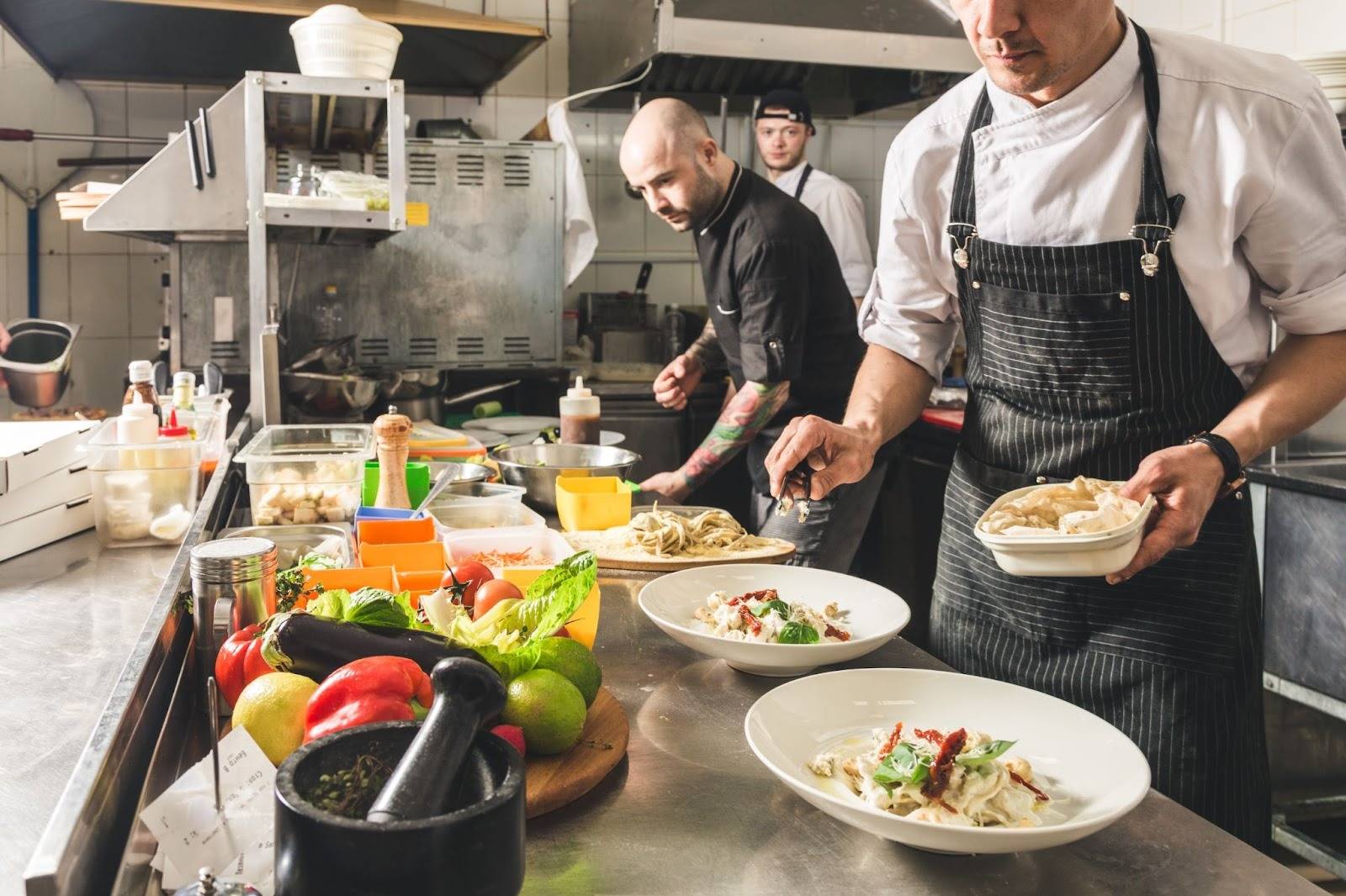 Chefs plating dishes in a commercial kitchen, illustrating safe food handling practices and the need for a certified food handler course in Canada.