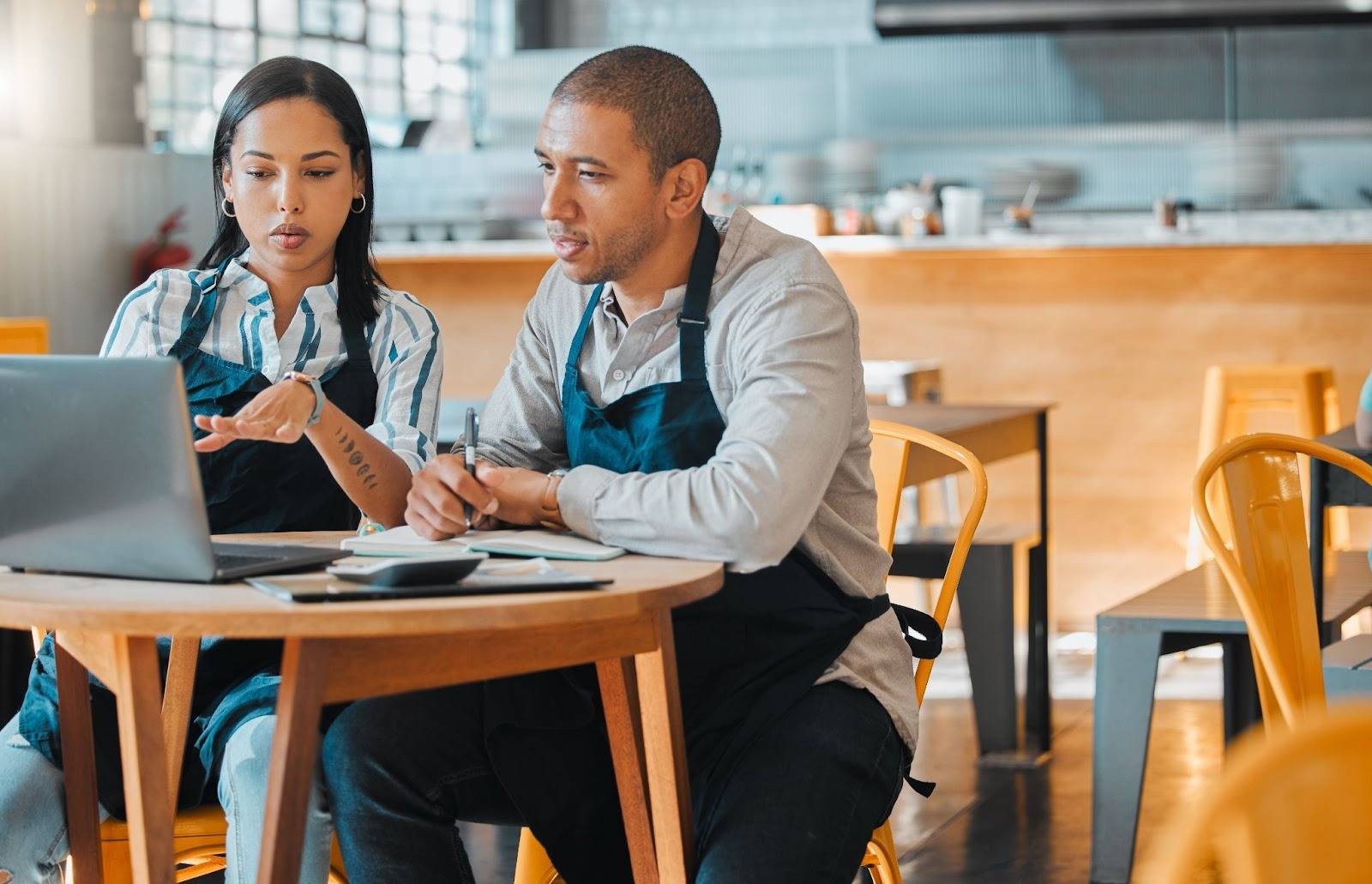 Restaurant employees reviewing food handler course renewal training on a laptop.