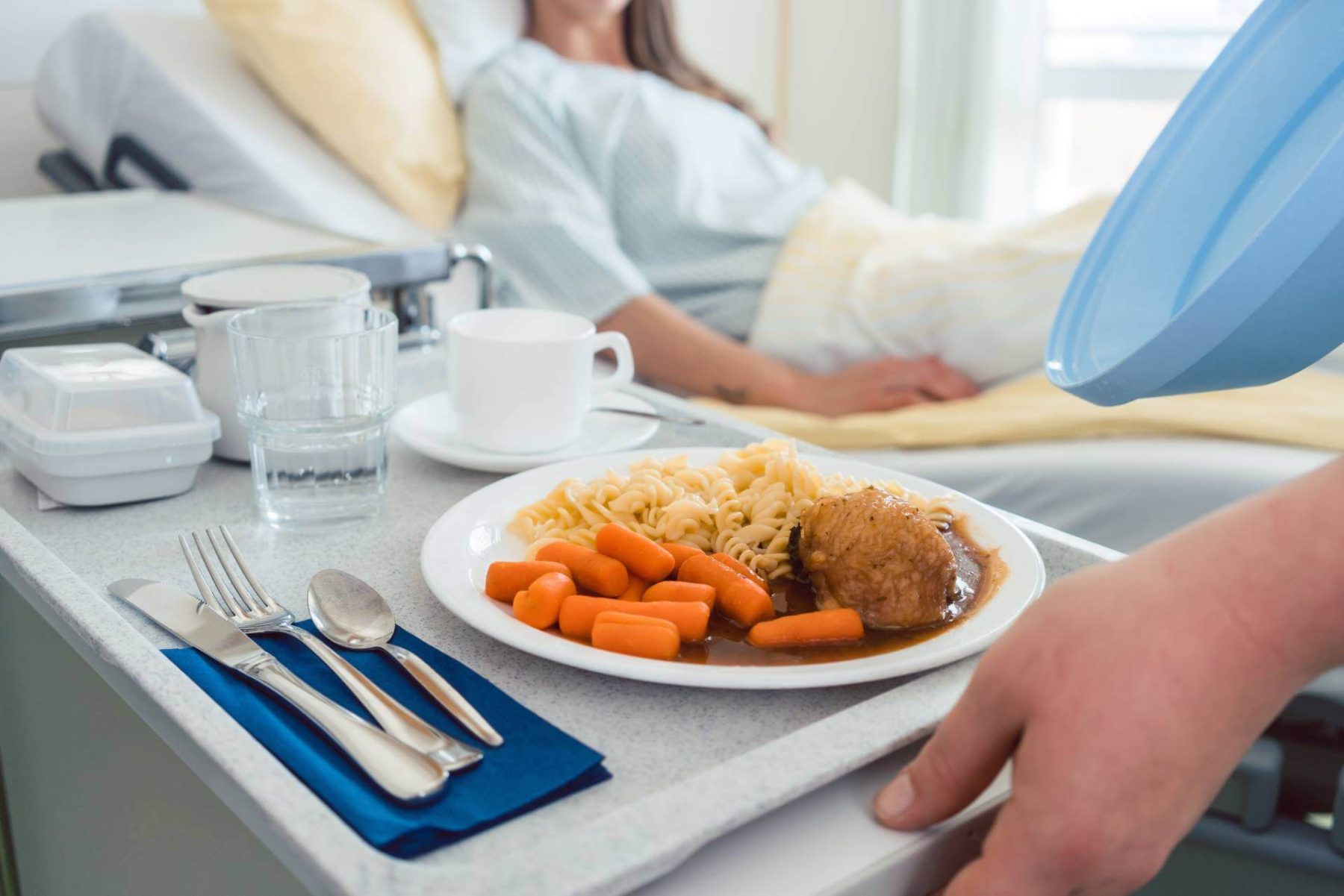 Hospital meal tray with food being served to a patient in bed.