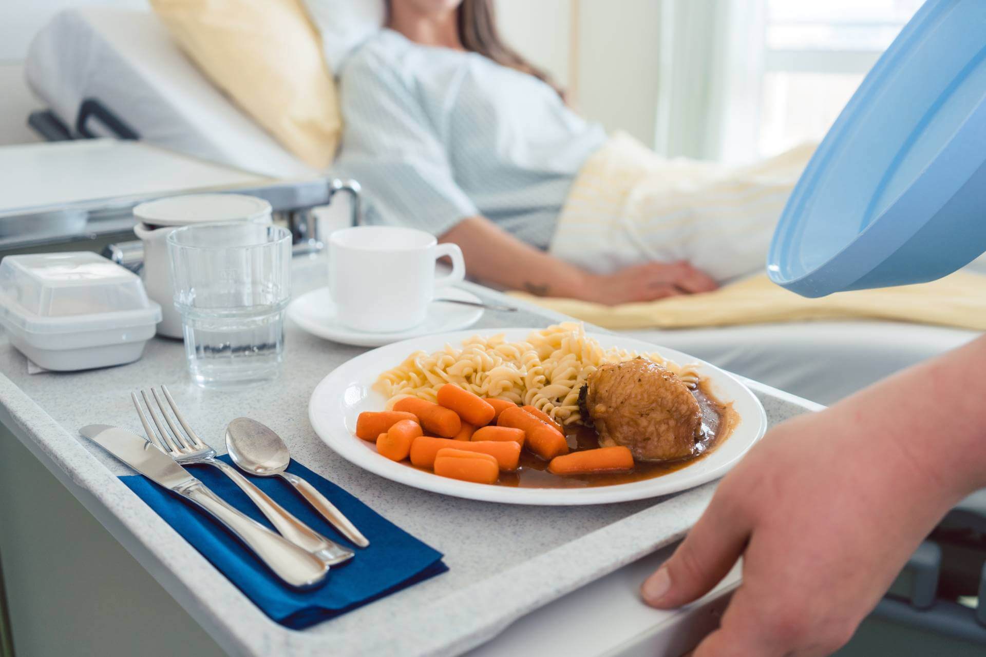 Hospital meal tray with food being served to a patient in bed.