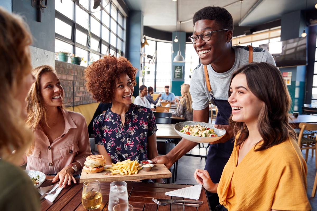 Restaurant server delivering food to a group of diners at a casual restaurant.